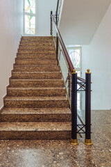 Stairs leading to upper floor with decorative railing and stained glass windows