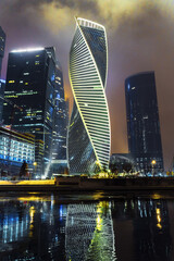 Modern buildingsshines at night in city skyline with reflections in water