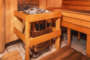 Inside a wooden sauna with rocks and benches set up for relaxation and warmth
