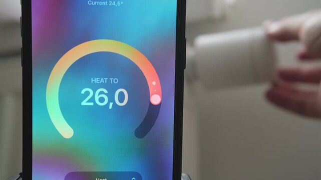 Male hand lowering thermostat temperature with real time update in mobile app.