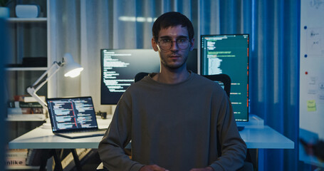 Portrait confident smile male programmer work with robotics code AI software and looking at camera in tech office night. Artificial intelligence dashboard, robotics, user interface, machine learning.