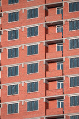 Obraz premium A fragment of the brick facade of a multi-storey residential building under construction on a winter day