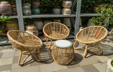 Garden decorated with outdoor wicker furniture and flower vase. fresh blooming potted plants for summer entertainment visits