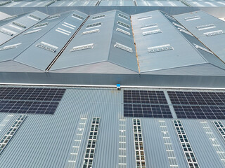 Aerial view of solar power plant with solar panels mounted on industrial building roof for producing green ecological electricity. Production of sustainable energy concept.