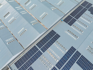 Aerial view of solar power plant with solar panels mounted on industrial building roof for producing green ecological electricity. Production of sustainable energy concept.