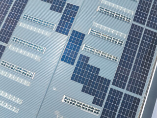Aerial view of solar power plant with solar panels mounted on industrial building roof for producing green ecological electricity. Production of sustainable energy concept.