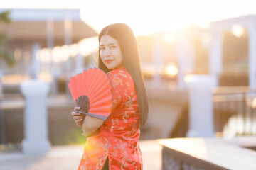 Portrait beautiful smiles Asian young woman wearing red traditional Chinese decoration and holding a Chinese Fanning  for Chinese New Year Festival at Chinese restaurant cafe.
