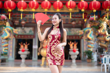 Asian woman wearing red cheongsam dress traditional decoration holding red envelopes in hand and lanterns with the Chinese text Blessings written on it Is a Fortune blessing for Chinese New Year