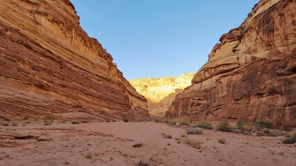 Desert Canyon Path Between Tall Red Rock Walls Under Clear Blue Sky