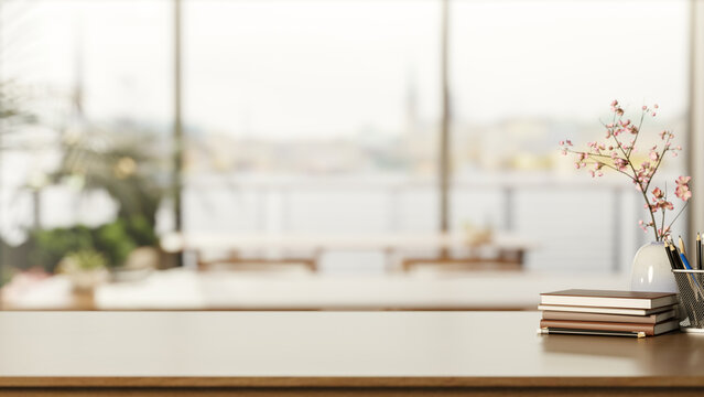 Books and pencil aside flower vase on wooden counter table across window wall in living room or cafe