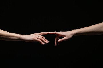 Two outstretched hands reach toward each other, fingers nearly touching, against a dark background. Symbolizes connection, longing, or creation with ample copy space