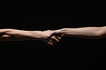 Two hands engage in a strong handshake, symbolizing agreement, trust, or partnership, against a black background with a high-contrast minimalist style