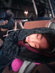 Sleeping while wearing a hoodie, a little girl is exhausted in the airport while traveling.