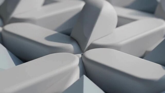 Close-up view of light gray, smooth, pill-shaped blocks arranged in a circular, interlocking pattern.