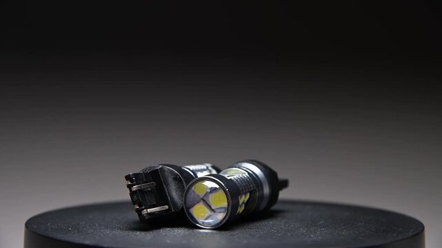 LED bulbs with different bases rotate on a gray gradient background. New parts for car interior and exterior lighting.