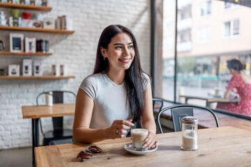 Mixed race woman drinking a cup of coffee at a table in cafe restaurant. 