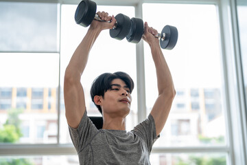 Asian young sportsman exercising to building muscle in gym stadium. 