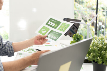 A diverse business team analyzing environmental charts and graphs in a collaborative meeting to create sustainable strategies in a modern office.