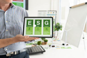 A diverse business team analyzing environmental charts and graphs in a collaborative meeting to create sustainable strategies in a modern office.