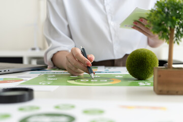 A diverse business team analyzing environmental charts and graphs in a collaborative meeting to create sustainable strategies in a modern office.
