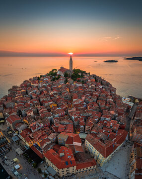 Rovinj, Croatia - Aerial panoramic view of the old town of Rovinj with Church of St. Euphemia and setting sun on a summer afternoon in Istria, Croatia. Gold and blue sky, red rooftops by the Adriatic
