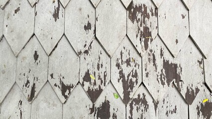 The texture of an old wooden wall with a geometric plank pattern and peeling paint creates a vintage and rustic feel.