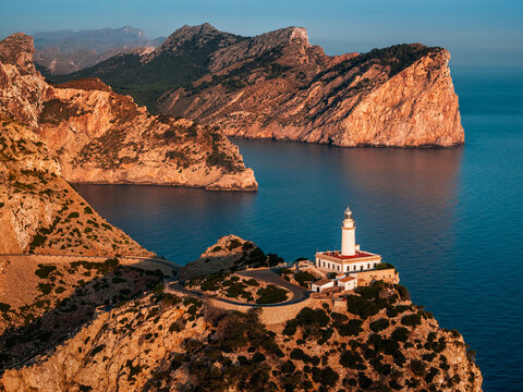 Mallorca, Spain - Aerial view of the Lighthouse at Cap de Formentor at sunrise with amazing cliffs and clouds and blue sky at background