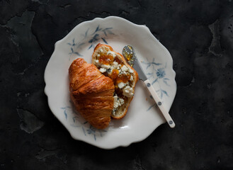 Croissant sandwich with fig jam and gorgonzola cheese on a dark background, top view