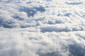 Aerial view of fluffy clouds seen from an airplane window flight.