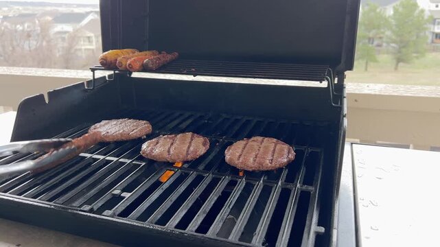 Turning Sausages While Burgers Grill Outdoors