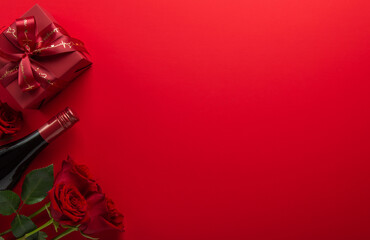 Gift, present box with red ribbon bow, rose flowers and wine bottle on red background top view. Valentine's day, 14 February, birthday, 8 march women's day gift. Love and romance.