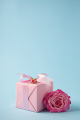 Gift, present box decorated with pink ribbon bow, pink rose flower on light blue background. Valentine's day, 14 February, birthday, 8 march women's day gift. Love and romance.