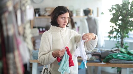  While shopping, woman looks at products in store and selects panties. Concept of seasonal wardrobe shopping. Client at shopping time leisure activity. 