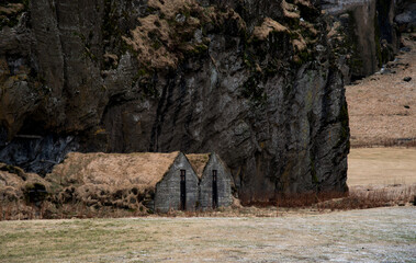 Drangshlio turf houses nestled under cliff in iceland