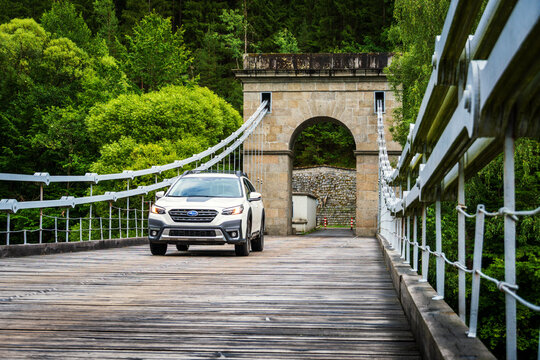 Stadlec, Czech Republic - June 12, 2025: Off-road family SUV Subaru Outback in white color stands on an old chain bridge over the Luznice River in South Bohemia.
