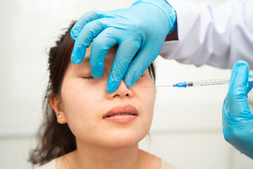 Asian woman receiving plastic surgery shape of nose performed on face.