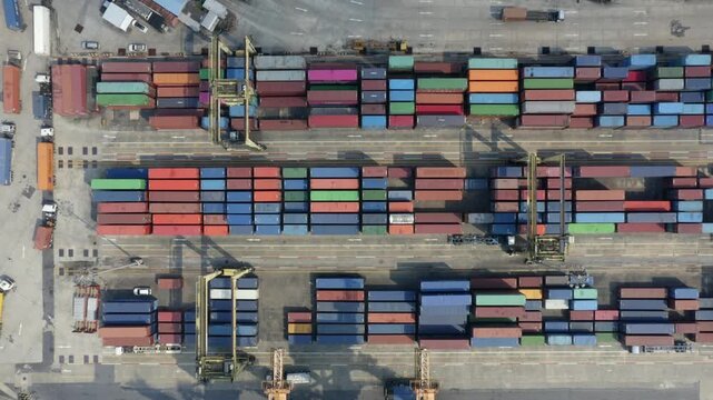 This dynamic video captures the bustling operations of a large-scale logistics port and shipping terminal, featuring massive container ships loading and unloading cargo, towering port cranes moving co