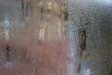 abstract background of wet glass. Condensation on glass window with blurred colors and moisture, unique textured background. close-up view of condensation forming textured, colorful pattern on glass.
