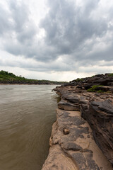 Rugged cliffs and rocky shores meet the turquoise waters of the stunning Mekong River bay along...