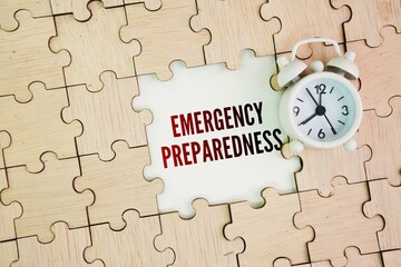 Clock and wooden puzzle with the word Emergency Preparedness. the steps you take to make sure you are safe before, during and after an emergency or natural disaster