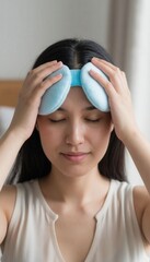 A person woman holding a small blue cushion resembling a cold compress, symbolizing home care, pain relief, comfort, and wellness, with visible copy space for health or lifestyle messaging.