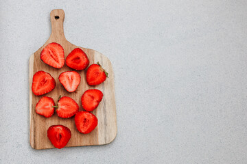 Freshly cut strawberries arranged on a wooden cutting board in a kitchen setting