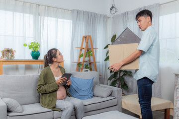 Pregnant woman sitting on couch, comforting stressed boyfriend holding head in hands, depicts...