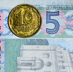 Ukrainian 10 kopiyok coin on a 5 hryvnia banknote, showing Ukraine money and currency background.