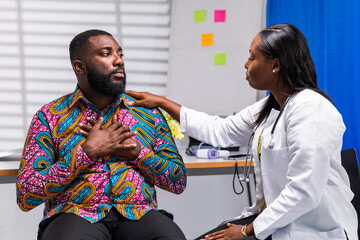 African female doctor comforts a distressed male patient in hospital during a consultation