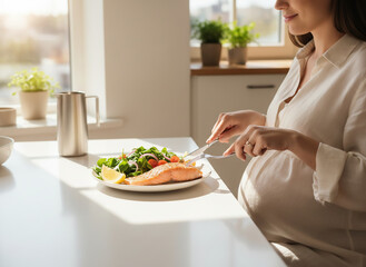 A pregnant woman sits at a bright kitchen table eating a healthy meal, highlighting balanced nutrition, wellbeing, and mindful lifestyle during pregnancy.