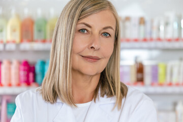 Positive and smiling mature woman in lab coat at the pharmacy