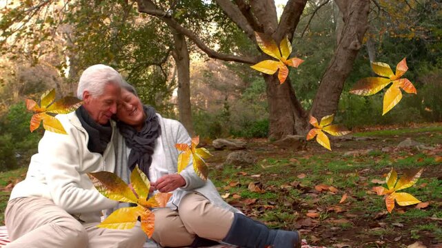 Animation of fall leaves floating over happy caucasian senior couple in autumn park