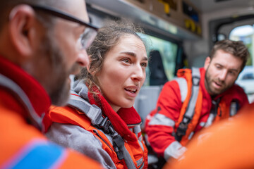 A paramedic is talking to family member, offering emotional support while another paramedic attends to patient