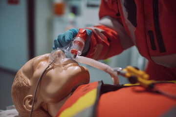 A paramedic is using suction device on medical dummy, clearing airway during crucial training scenario
